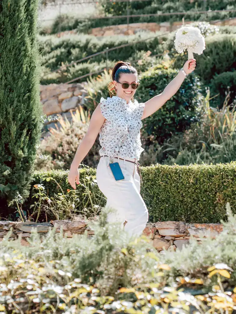 Claudia Magni hurrying through a garden with the bride’s bouquet raised